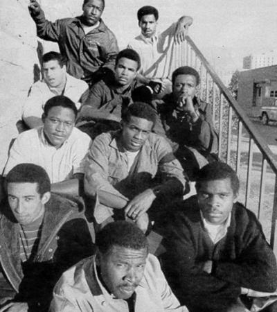 Ten of the Black 14 sitting on an outdoor stairway.